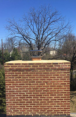 Stock photo of chimney brick and mortar repair after completion trees in the background.  Nice clean crown and new cap.