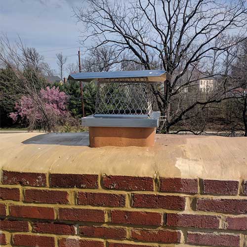 Stock photo of new chimney cap and new crown with trees in the background.