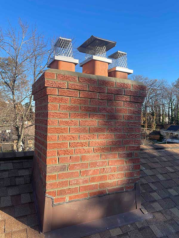 Three new chimney caps and flues with new Crown.  Winter trees in the background.