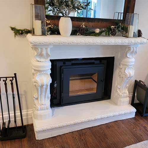 Stock photo of beautiful white victorian-like fireplace surround with black insert tools on the left and a mirror over the mantel.
