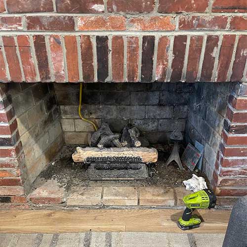 Stock photo of gas log set before new installation.   Surround is brick and there is only one log.  Firebox is nasty.