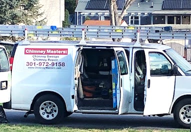 Chimney Masters Van with ladders on top in front of a store.