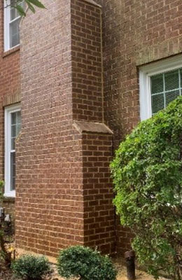 Stock photo of nice chimney after soot removal.  Windows in the background and landscaping in the foreground.
