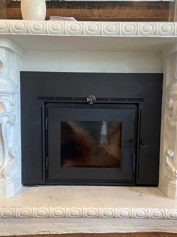 Stock photo of Victorian style fireplace with wood burning insert after completion.  Plain and simple flat black with a door and window.