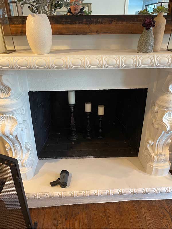 Stock photo of beautiful Victorian style fireplace with candles inside and a flashlight on the hearth.  The mantel is decorated with vases with a mirror in the background.